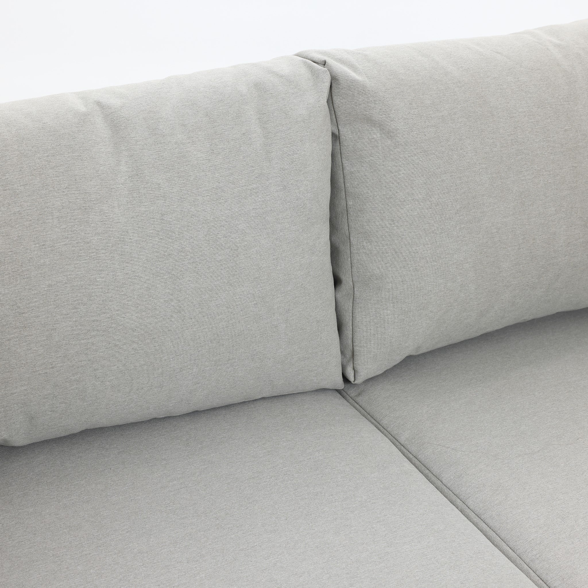 Close-up of a light gray sofa with two back cushions and a seat, showcasing its fabric texture and stitching details, seamlessly complementing an outdoor conversation set.