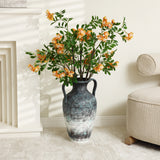 A LuxenHome mottled gray ceramic tall vase stands at 18.5 inches, featuring handles and holding vibrant orange flowers with green leaves. Its placed on a light floor by a white wall near a soft armchair, creating a minimalist scene where sunlight casts gentle shadows.