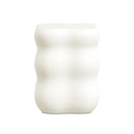 A white, ribbed vase with a wavy, cylindrical shape stands elegantly against a plain background, seamlessly fitting into the realm of modern home furnishings.