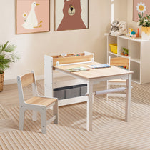 A childrens playroom features a LuxenHome Children Play Table with Bookcase and 2 Chairs set on a striped wooden floor, stocked with pens and paper. Framed animal art of a goose and bear adorns the walls. Plush toys and storage bins line the shelves, while a potted plant adds charm nearby.