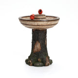 Decorative polyresin garden birdbath featuring a tree trunk-like base and two red bird figurines on the rim, perfect as an outdoor decor centerpiece.