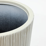 Close-up of a white, ribbed cylindrical object with a dark interior, reminiscent of modern planters made from durable polyethylene, against a plain background.