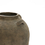 A close-up shows a LuxenHome 15.4 Rustic Brown Terracotta Cauldron Vase, its aged surface exuding natural elegance. The rough texture and two broken handles are partially in view against a plain white backdrop.