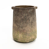 A weathered, cylindrical stone pot with two small handles near the top showcases a rustic ginger root brown finish. Its rough texture and shades of green and brown enhance its charm, making it reminiscent of a traditional rustic vase.