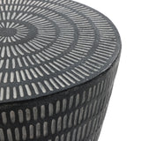 The LuxenHome Meru outdoor end/side table features a round, textured surface with concentric patterns. Crafted from durable magnesium oxide, its geometric optical illusion effect combines alternating light and dark lines with a modern black finish.