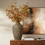 A LuxenHome rustic brown terracotta urn vase (14.6 high) filled with autumn foliage sits on a wooden sideboard. Nearby, books and a decorative item add to the scene, while an abstract painting in browns and creams completes the elegant rustic vibe.