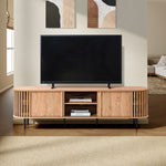 A mid-century modern TV cabinet with a flat-screen TV sits on a wooden stand with shelves, holding books. Its set against a living room wall adorned with abstract art, perfectly complementing the sleek sliding door design nearby.