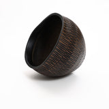 The LuxenHome dark brown textured resin round planter, large, sits tilted on a white background. It features vertical grooves for an artisanal and rustic design.