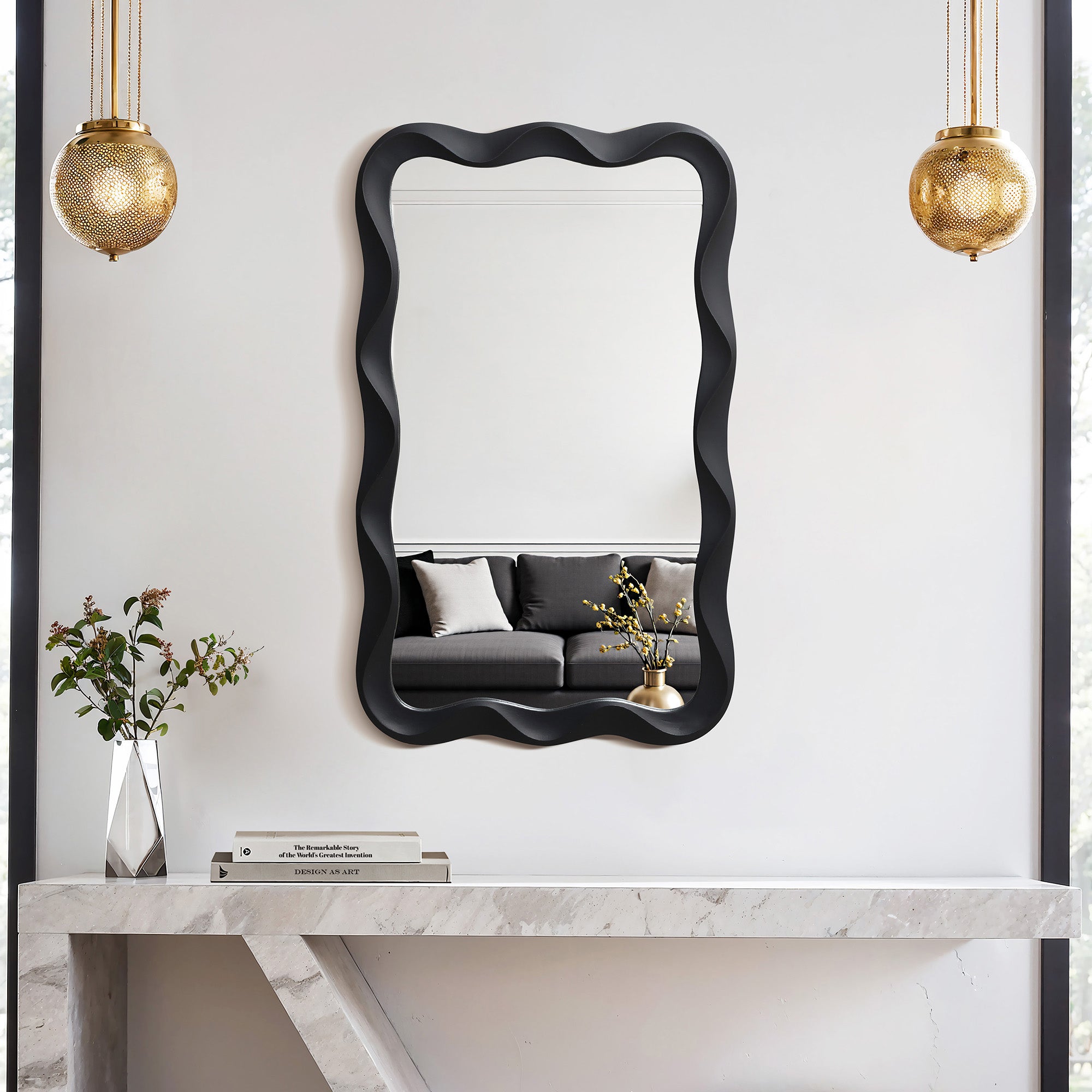 Wavy frame mirror hangs above a marble console table, flanked by two gold pendant lights.