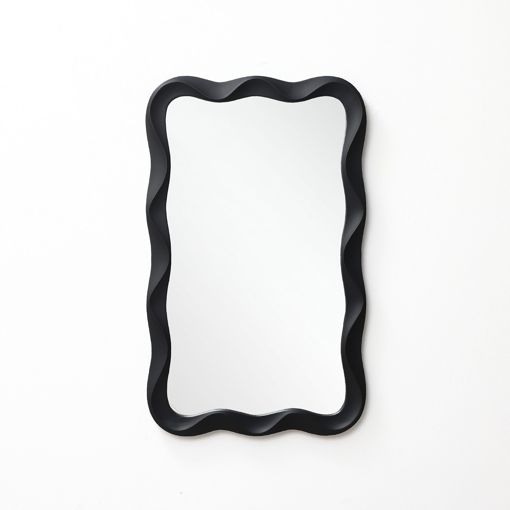Modern wall mirror featuring a black, wavy, scalloped frame, mounted on a plain white wall.