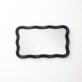 Modern wall mirror featuring a wavy black frame adds a stylish touch, beautifully mounted on a white wall.