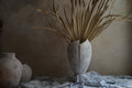 vintage like weathered finish crack open ceramic vase with dried tropical leave in low light environment by the window