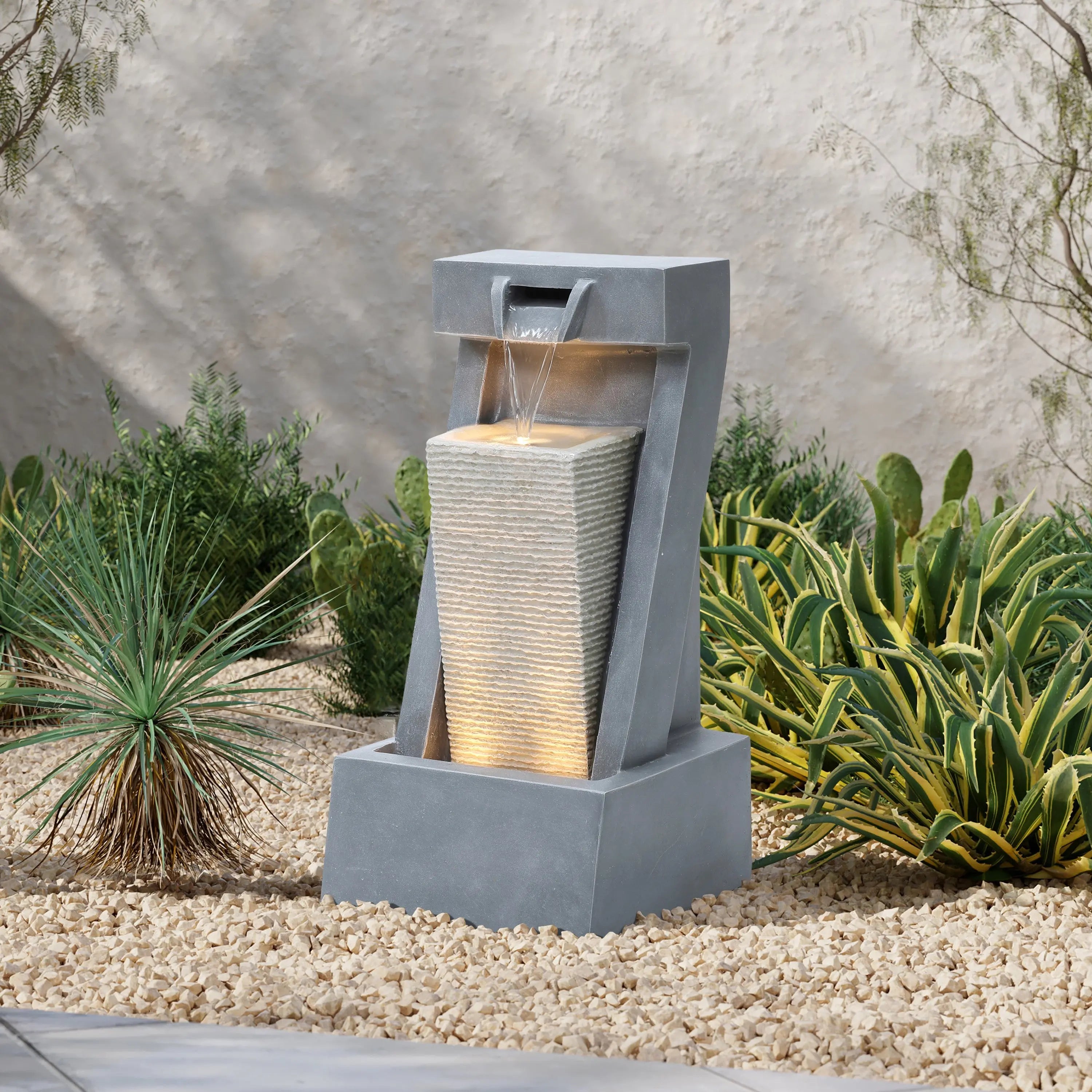 Outdoor LED fountain with two gray resin columns illuminated at dusk on a patio