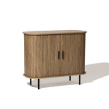 Mid-Century Modern Accent Cabinet featuring an oak grain finish, with rounded edges, two front slatted tambour doors, vertical grooves, and black metal legs.