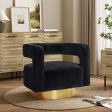 A modern accent chair with a black velvet finish and curved backrest on a gold base offers 360-degree rotation, sitting elegantly on a round beige rug. In the background, wooden cabinets, framed art, and a potted plant complete the stylish scene.