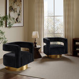 A modern living room features two black velvet finish accent chairs with gold bases, a small wooden side table with a lamp, large window with trees outside, and a potted plant on a soft beige carpet.