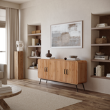 A modern living room showcases the Randolph wood accent sideboard by LuxenHome, featuring three drawers and cabinet doors for ample storage. Built-in shelves display books, vases, and decor. A large abstract painting hangs above the sideboard, with neutral tones and wood flooring completing the scene.