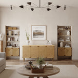 A testament to natural modernism, this living room features wooden furniture and handcrafted jute woven doors. Two bookshelves with adjustable shelves flank a central sideboard, and a round coffee table rests under a geometric ceiling light. A framed abstract artwork elegantly adorns the space above the sideboard.