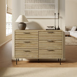 In a modern living room, the LuxenHome Casper mid-century 6-drawer dresser with metal legs showcases its wave-shaped brown wood grain design. A lamp and two tall candlesticks sit on top alongside books, as sunlight streams through the window, illuminating neutral-toned decor and a sofa in the background.