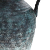 Close-up of a textured, weathered LuxenHome Mottled gray ceramic tall vase, 18.5 h, showcasing shades of green and blue patina. Its surface reveals minimalist refinement through roughness and subtle color variations, indicating age and intricate craftsmanship.