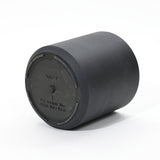 A black cylindrical drum with a flat top, ideal for planters, features an embossed instruction that reads, For outdoor use. Drill hole here. Crafted to be durable, it promises long-lasting performance in any outdoor setting.