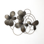Bronze-colored metal wall sculpture featuring abstract flower petals and circular loops arranged.