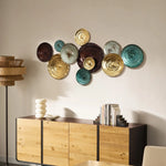 A wall with colorful round ceramic plates serves as an abstract design element in the interior. Below is a wooden sideboard adorned with books, a lamp, and a decorative object.