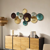 A wall with colorful round ceramic plates serves as an abstract design element in the interior. Below is a wooden sideboard adorned with books, a lamp, and a decorative object.