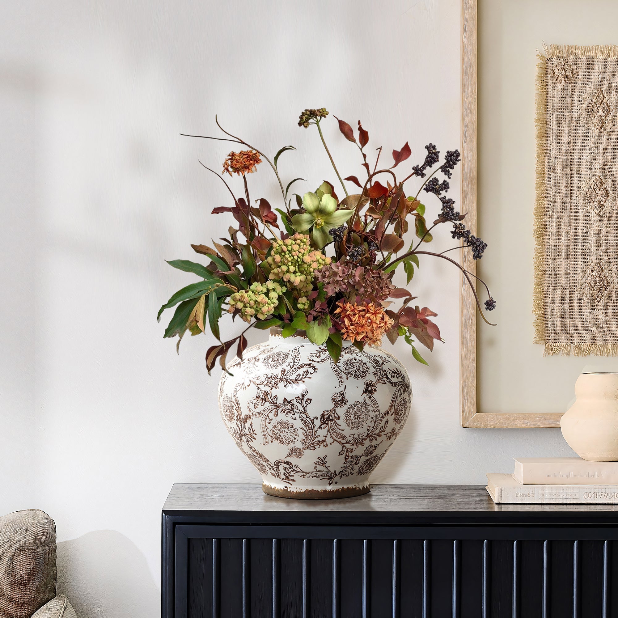 Elegant vase with brown floral patterns holds artificial autumn flowers and greenery.