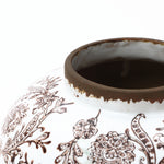 Close-up of the top part of an elegant vase with brown floral patterns and a worn, dark brown rim.