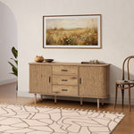 Buffet cabinet sideboard, a mid century storage cabinet with three drawers and two cabinets, placed against a white wall below a framed landscape painting, with a rug, chair, and potted plant completing the room scene.