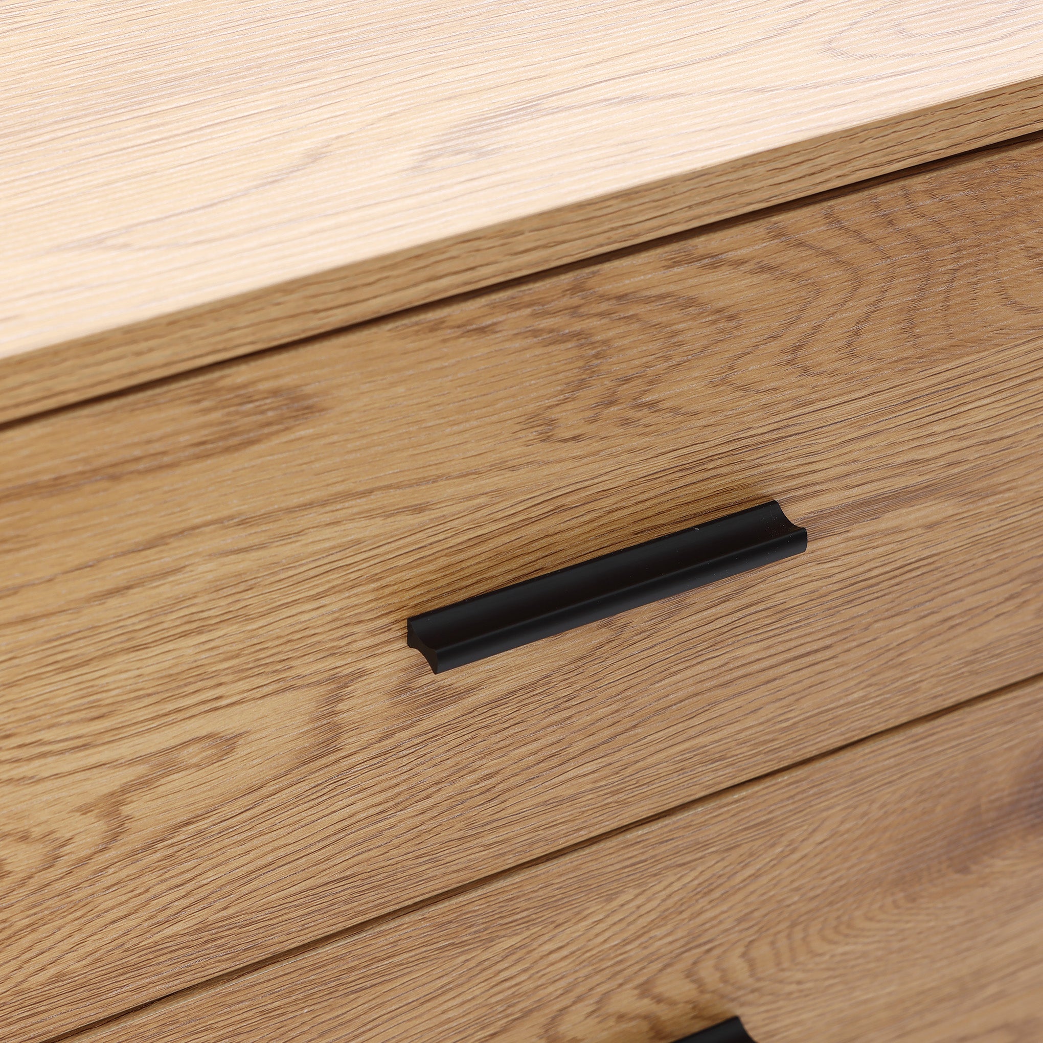 Buffet cabinet sideboard, close-up of two wooden drawers with black metal handles, highlighting the oak wood grain texture and clean mid century design.