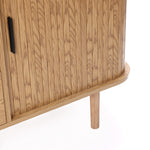 Buffet cabinet sideboard, close-up of a mid century storage cabinet with vertical oak grain, black handle, rounded edge, and one cylindrical leg visible on a white background.