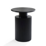 A black cylindrical side table with a ribbed base and smooth round top showcases a modern aesthetic against a white background, accented by hints of natural wood grain.