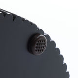 Close-up of a black, scalloped-edge object with a round, textured button on its surface, exuding a modern style and decorative effect.