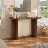 A minimalist wooden console table adorned with vases, a basket, and a decorative item is positioned against a wall showcasing an abstract painting. Nearby, another basket sits as sunlight gently streams through the window, evoking a mid-century modern charm.
