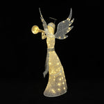 Pre-lit angel holding a trumpet stands in the snow outside,surround by illuminated trees ,lanterns.