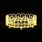Circular, decor fence with scroll pattern by bright yellow led fence lights against black background.