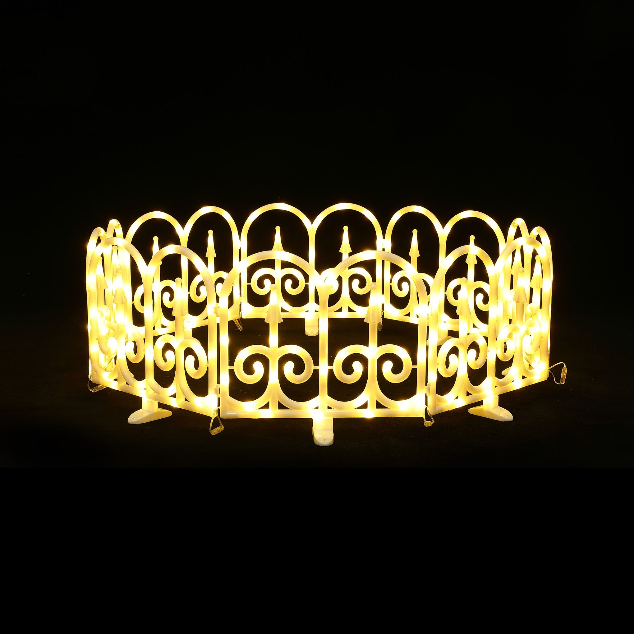 Circular, decor fence with scroll pattern by bright yellow led fence lights against black background.