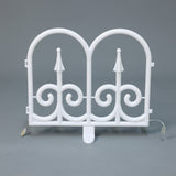 White plastic decor led fence piece with 2 arched tops ,swirl, standing upright against a plain gray background.