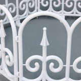 White metal led fence with decor scrollwork  pointed finial, set against a plain gray background.