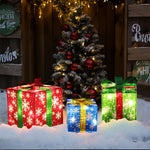 Three illuminated LED gift boxes in red, blue, and green sit on snow as festive holiday decor.