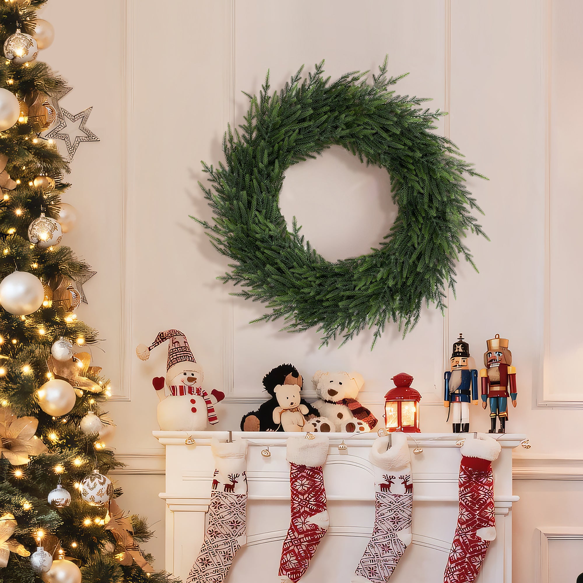 Artificial wreath hangs on a white wall above a mantel adorned with stockings, nutcrackers, plush toys, lit lantern.