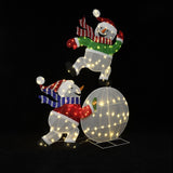 2 pre snowman holiday decor pieces, one with a red scarf , the other with green, balance playfully on a lit globe.
