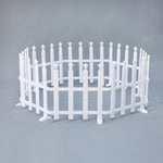 Small, white, circular picket fence with star-shaped tops on each post, set against plain gray background.