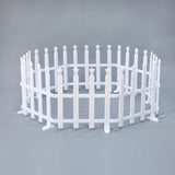 Small, white, circular picket fence with star-shaped tops on each post, set against plain gray background.