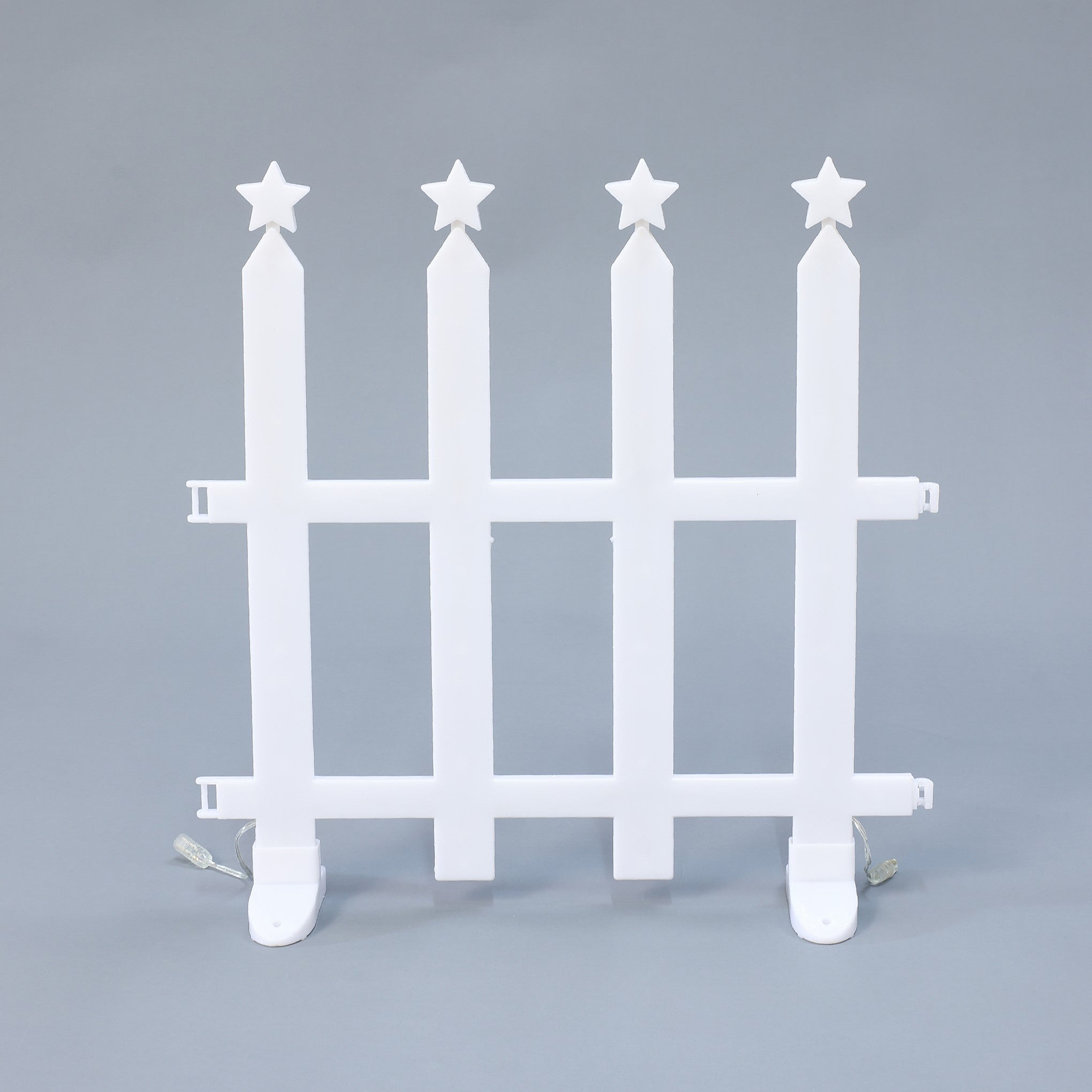 White plastic picket fence with 4 vertical posts, each topped with 5 pointed star, against plain gray background.