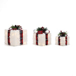 3 white faux fur gift boxes with plaid ribbons, decor with pine greenery, red berries.