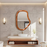 Modern bathroom featuring an asymmetrical wall mirror with a wood frame above a white sink.
