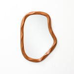 Asymmetrical wall mirror with a wooden wavy-edged frame, perfect as a striking to elevate modern home décor.